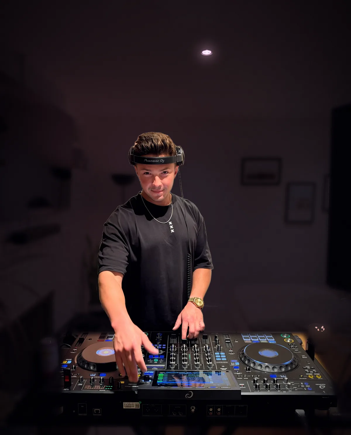 Don Vaughan behind the decks with his headphones on, looking into the camera
